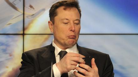 SpaceX founder and chief engineer Elon Musk looks at his mobile phone during a post-launch news conference to discuss the SpaceX Crew Dragon astronaut capsule in-flight abort test at the Kennedy Space Center in Cape Canaveral, Florida.