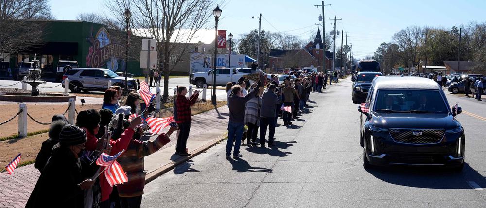 Trauernde versammeln sich, als der Leichenwagen mit dem in die Flagge gehüllten Sarg des ehemaligen US-Präsidenten Jimmy Carter am 4. Januar 2025 durch Ellaville, Georgia, fährt.
