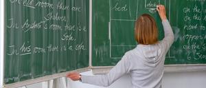 Eine Englisch-Lehrerin einer Grundschule schreibt Unterrichtsinhalte an die Tafel.