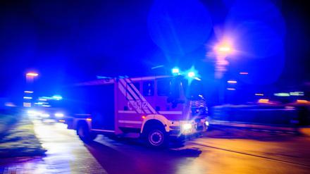 Ein Feuerwehrfahrzeug fährt mit Blaulicht durch die Nacht. (Symbolbild)