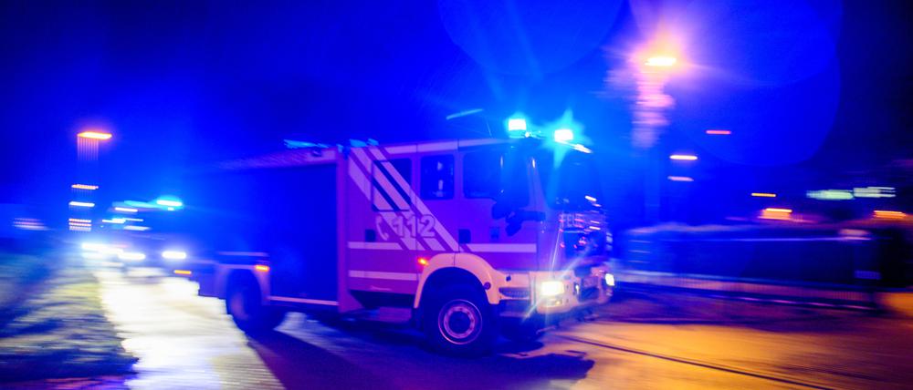 Ein Feuerwehrfahrzeug fährt mit Blaulicht durch die Nacht. (Symbolbild)