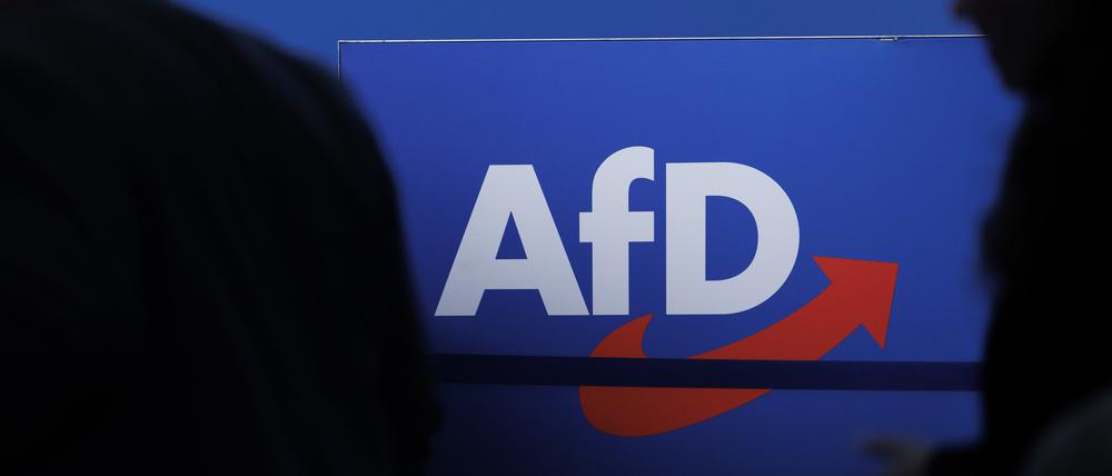 ARCHIV - 28.07.2023, Sachsen-Anhalt, Magdeburg: Delegierte gehen vor dem Parteilogo bei dem AfD-Bundesparteitag in Magdeburg. (zu dpa: «Behörden prüfen Entwaffnung von AfD-Mitgliedern») Foto: Carsten Koall/dpa +++ dpa-Bildfunk +++
