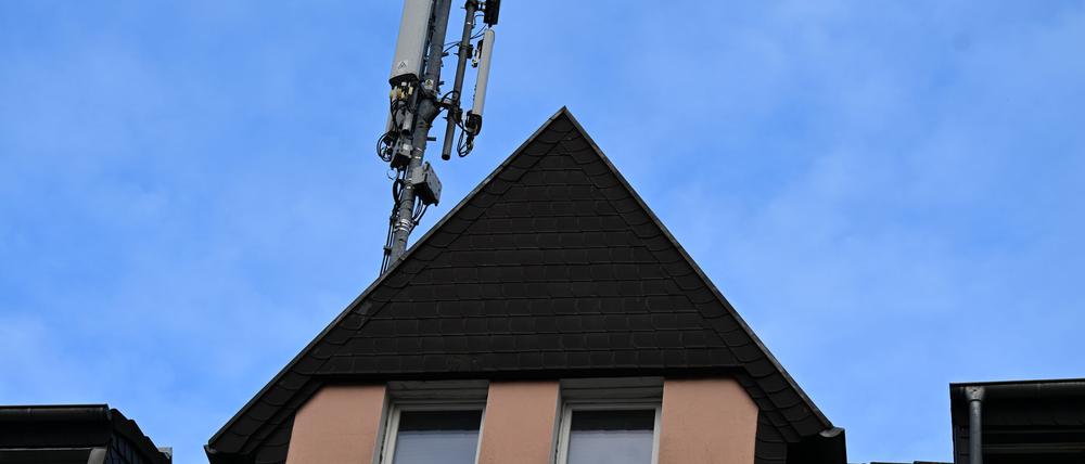 Ein Mobilfunk-Mast mit Antennen im Funkstandard 5G (quadratisch) und 4G (länglich) ist auf dem Dach eines Wohnhauses montiert.