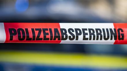 Ein Absperrband mit der Aufschrift «Polizeiabsperrung» vor einem Polizeiwagen. 