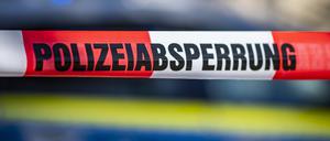 Ein Absperrband mit der Aufschrift «Polizeiabsperrung» vor einem Polizeiwagen. 