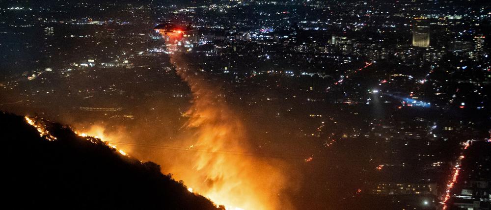 Ein Hubschrauber wirft Wasser auf das brennende Sunset Fire in den Hollywood Hills.