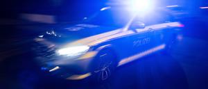 Ein Polizeifahrzeug fährt mit Blaulicht an einem Gebäude vorbei. 