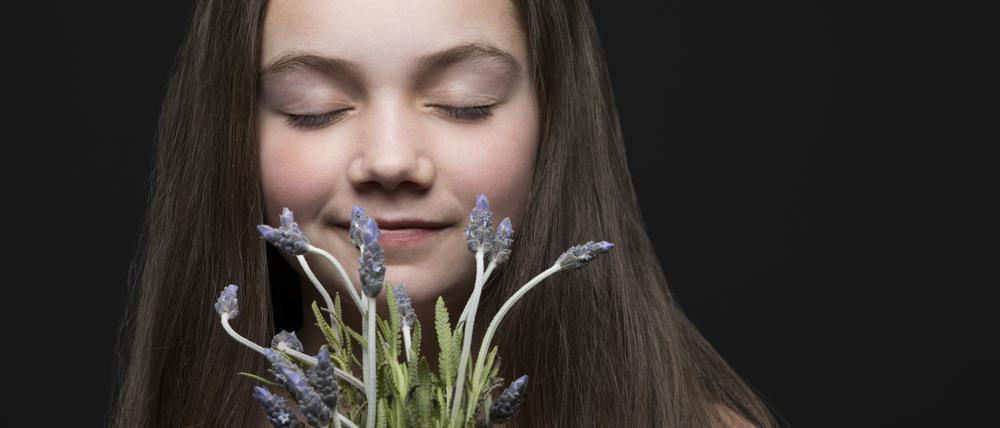 Ein Mädchen riecht an Blumen.