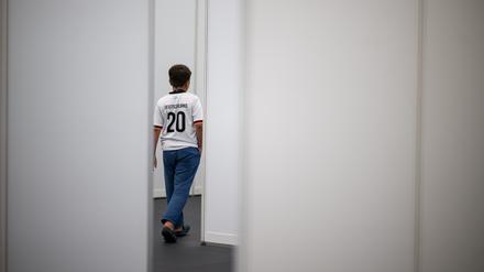 Ein neunjähriger Junge aus Syrien, der ein Deutschland-Trikot trägt, geht im Ankunftszentrum am ehemaligen Flughafen Tegel durch einen Gang.