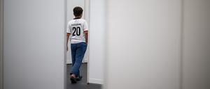 Ein neunjähriger Junge aus Syrien, der ein Deutschland-Trikot trägt, geht im Ankunftszentrum am ehemaligen Flughafen Tegel durch einen Gang.