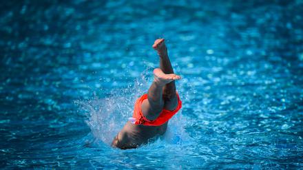 18.07.2024, Berlin: Ein Junge springt im Sommerbad Neukölln ins Schwimmbecken.