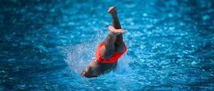 18.07.2024, Berlin: Ein Junge springt im Sommerbad Neukölln ins Schwimmbecken.