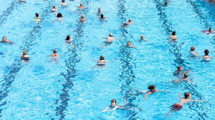 Menschen schwimmen im Wasser eines Freibads (Symbolbild)