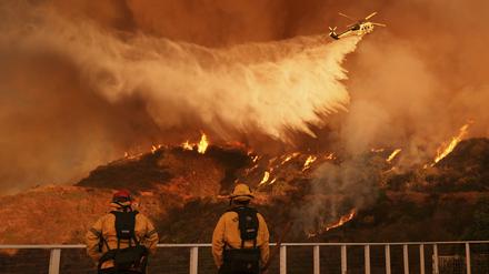 Feuerwehrleute beobachten, wie Löschwasser auf das Palisades-Feuer im Mandeville Canyon Angeles geworfen wird.