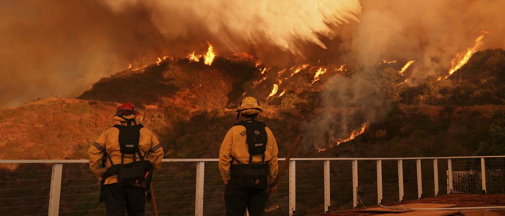 Feuerwehrleute beobachten, wie Löschwasser auf das Palisades-Feuer im Mandeville Canyon Angeles geworfen wird.