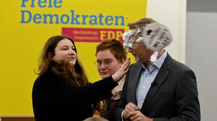 Der FDP-Vorsitzende Christian Lindner bekommt bei einem Wahlkampfauftritt in Greifswald von der Linke-Lokalpolitikerin Christiane Kiesow (l) Schaum ins Gesicht geworfen. Er war von einer jungen Frau mit Schaum beworfen worden. Sie traf den früheren Finanzminister dabei direkt ins Gesicht. Nach dem Vorfall setzte er seine Rede fort.