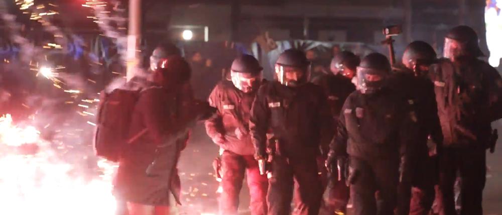 Polizisten stehen in der Silvesternacht zwischen brennendem Feuerwerk. (Symbolbild)