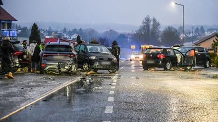 Nach einem Unfall bei Glatteis mit mehreren Fahrzeugen in Baden-Württemberg stehen Helfer und Beteiligte an den Autos auf einer Straße. 
