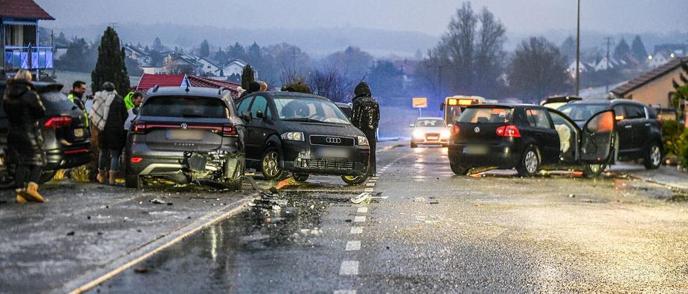 Nach einem Unfall bei Glatteis mit mehreren Fahrzeugen in Baden-Württemberg stehen Helfer und Beteiligte an den Autos auf einer Straße. 