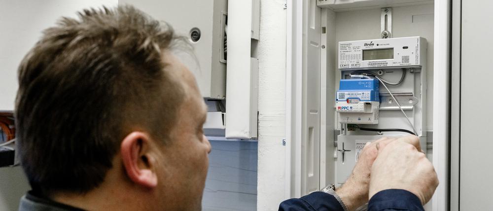 Ein Elektriker montiert einen digitalen Stromzähler mit einem Smart-Meter-Gateway zur Datenübertragung.