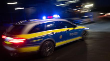 Ein Polizeifahrzeug fährt mit Blaulicht an einem Gebäude vorbei. 