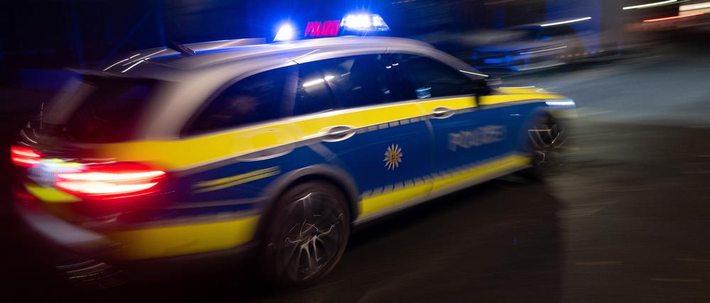 Ein Polizeifahrzeug fährt mit Blaulicht an einem Gebäude vorbei.