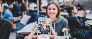 Eine junge Frau wird mit einem Smartphone fotografiert.