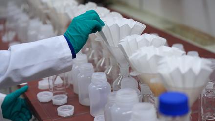 Eine Laborantin steckt Filter für Abwasserproben in die Öffnung von Gefäßen im Labor von Hamburg Wasser auf dem Gelände des Klärwerks Köhlbrandhöft. Hamburg Wasser hat den Wasserreport 2024 vorgestellt.