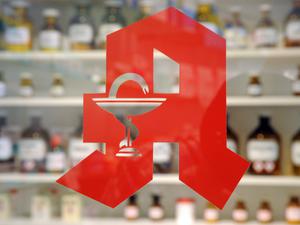 Das Logo ist an der Tür einer Apotheke zu sehen.