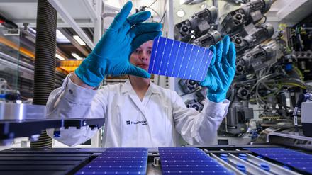 Eine Mitarbeiterin des Fraunhofer-Centers für Silizium-Photovoltaik CSP prüft die Leitklebestruktur einer Solarzelle nach dem Kleben in einem Zellstringer.