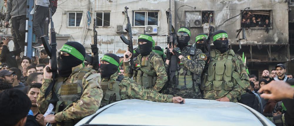 Kämpfer der Qassam-Brigaden, des militärischen Flügels der Hamas, stehen auf einem Auto, als Fahrzeuge des Roten Kreuzes zur Abholung israelischer Geiseln, die im Rahmen eines Waffenstillstandsabkommens zwischen Israel und der Hamas freigelassen wurden, in Gaza-Stadt rangieren.