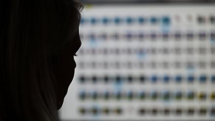 Eine Ermittlerin sitzt im Landeskriminalamt Hessen vor einem Monitor mit Fotodateien.