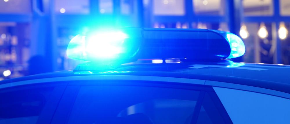 Ein Streifenwagen der Polizei steht mit eingeschaltetem Blaulicht an einem Einsatzort.