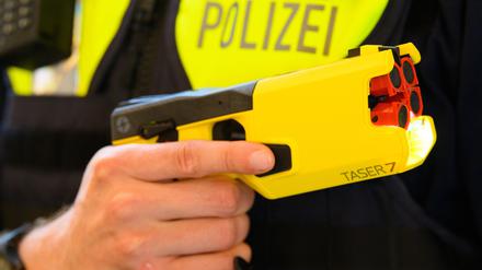 Ein Polizeibeamter hält im Rahmen der Pressekonferenz des Polizeipräsidenten einen Taser in der Hand.