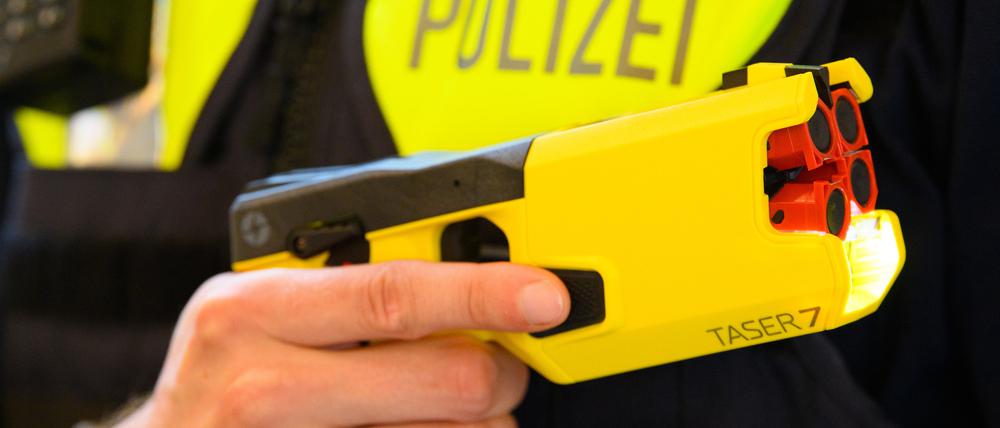 Ein Polizeibeamter hält im Rahmen der Pressekonferenz des Polizeipräsidenten einen Taser in der Hand.