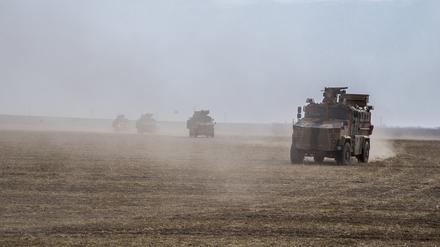 Militärfahrzeuge wirbeln Staub auf, während sie über ein Feld nahe der Grenze zu Syrien fahren.