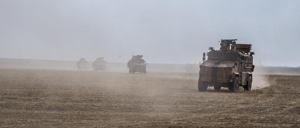 Militärfahrzeuge wirbeln Staub auf, während sie über ein Feld nahe der Grenze zu Syrien fahren.