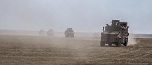  Militärfahrzeuge wirbeln Staub auf, während sie über ein Feld nahe der Grenze zu Syrien fahren. 