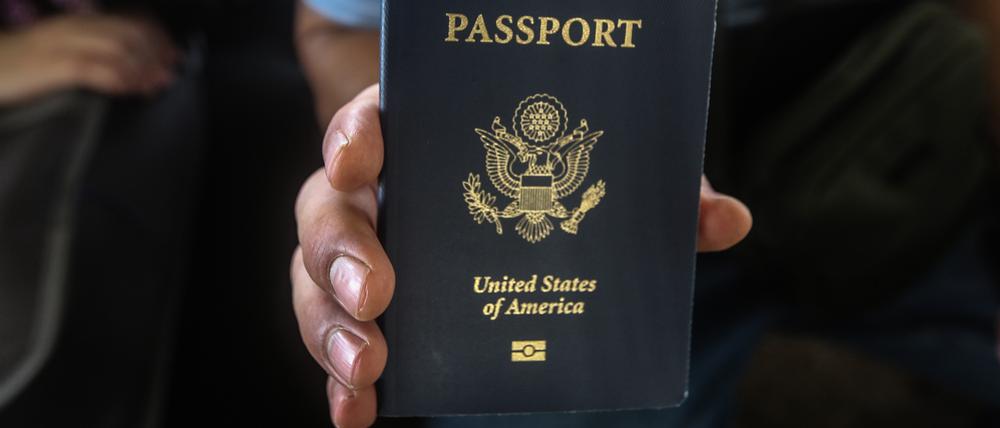 Ein US-Bürger hält seinen Reisepass in der Hand.