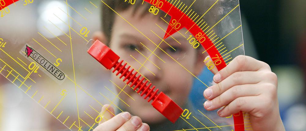 Ein Junge hält ein Geodreieck in den Händen.