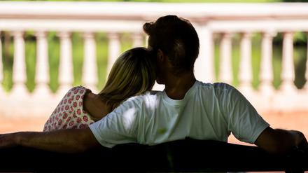 Eine Frau und ein Mann sitzen zusammen auf einer Parkbank (gestellte Szene).