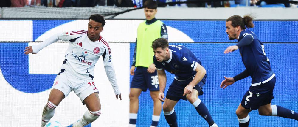 Die KSC-Spieler Leon Jensen (m) und Sebastian Jung (r) attackieren den Düsseldorfer Myron van Brederode (l).