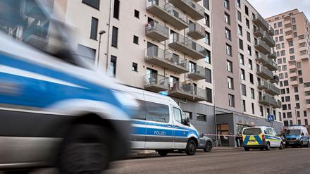 Polizeifahrzeuge stehen vor dem Wohngebäude. Im Fahrstuhl des Wohnhauses in Berlin-Marzahn ist nach Polizeiangaben eine schwer verletzte Frau gefunden worden, die kurz darauf gestoben ist.