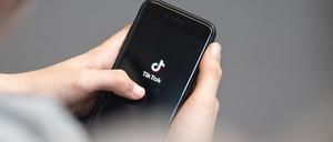 Eine Jugendliche schaut auf ein Smartphone mit angezeigtem TikTok-Logo.
