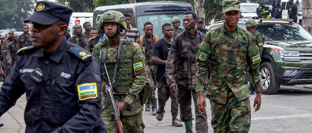 Ruandische Sicherheitskräfte eskortieren Soldaten der regulären Armee der Demokratischen Republik Kongo, die sich den Rebellen in Goma ergeben haben.