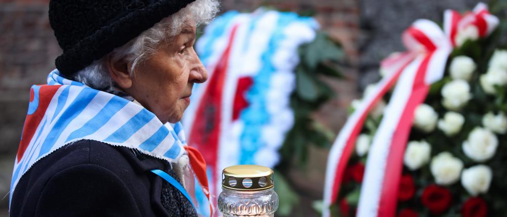 Eine Überlebende stellt ein Licht an die Todeswand im Stammlager Auschwitz I.