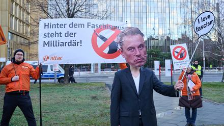 Aktivistinnen und Aktivisten von Attac stehen mit Slogans, wie „Hinter dem Faschismus steht der Milliardär!“ und einer Musk-Maske vor dem Axel-Springer-Hochhaus und demonstrieren, kurz vor dem «Welt»-Wirtschaftsgipfel.