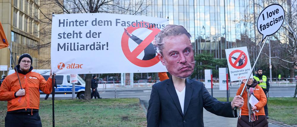 Aktivistinnen und Aktivisten von Attac stehen mit Slogans, wie „Hinter dem Faschismus steht der Milliardär!“ und einer Musk-Maske vor dem Axel-Springer-Hochhaus und demonstrieren, kurz vor dem «Welt»-Wirtschaftsgipfel.