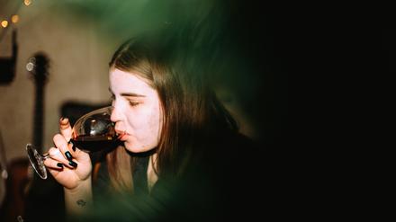 Eine junge Frau trinkt ein Glas Wein auf einer Party.