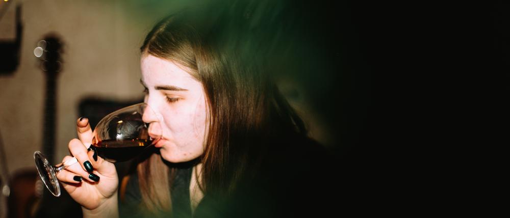 Eine junge Frau trinkt ein Glas Wein auf einer Party.